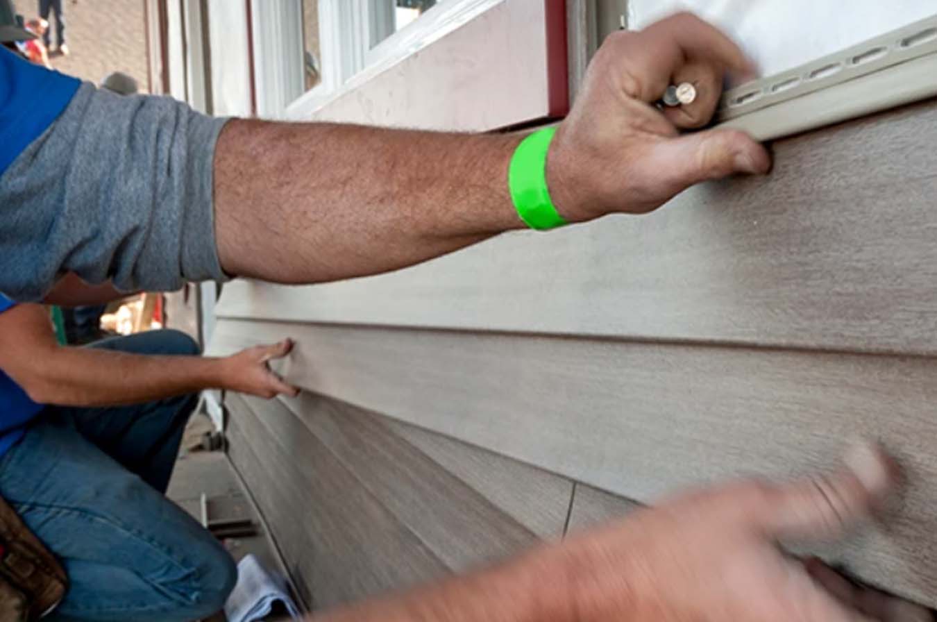 Professional contractor installing ply gem siding by mastic in a Bowling Green, Ohio house