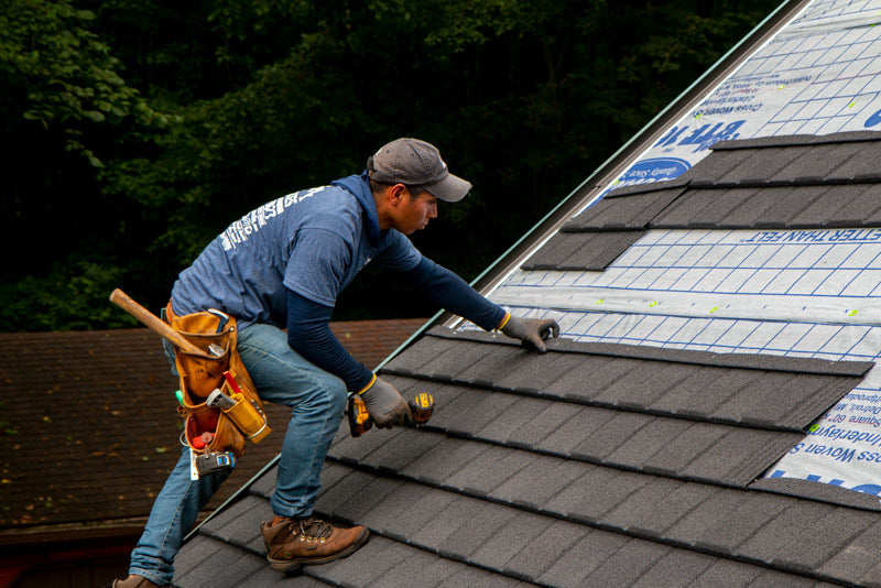 Roofing contractor installing metal shingle panels on a roof